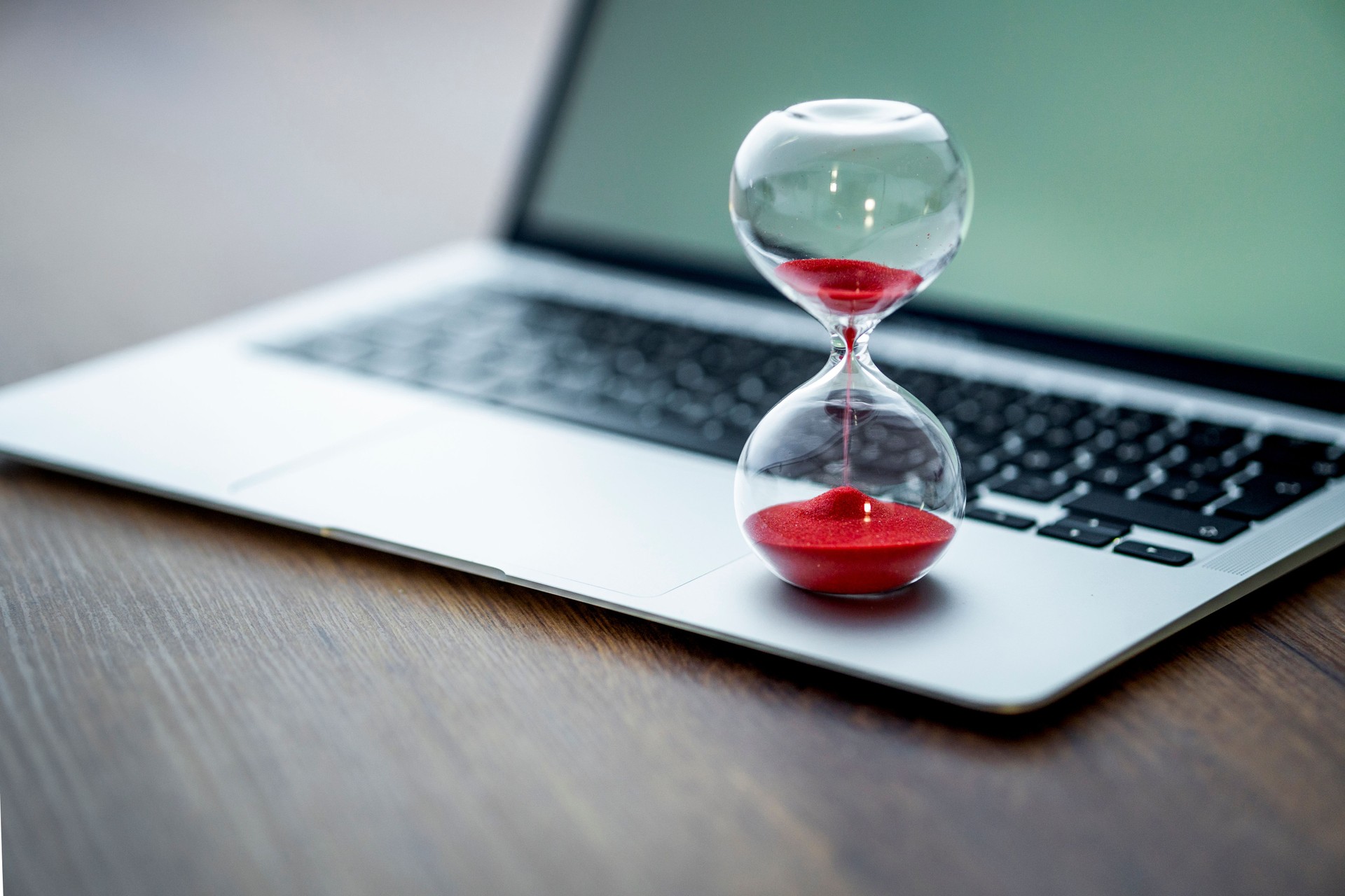 Red hourglass on laptop symbolizes time management and deadlines. Crisp details. Concept for productivity and work organization themes